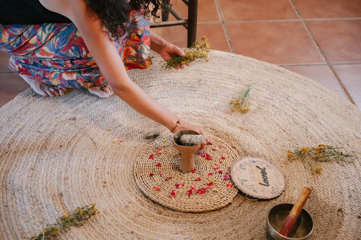 Preparació d’un ritual amb herbes, pètals i un bol tibetà sobre una catifa